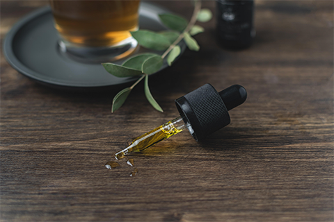 CBD Oil Dropper on a Table With a Drink