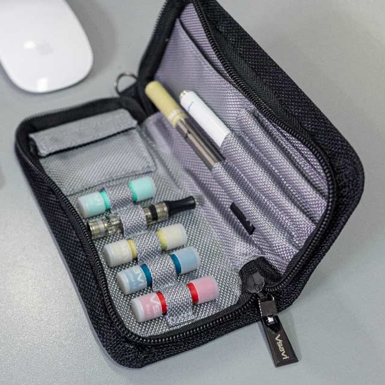 Black carrying case with vape pens and accessories on a light gray surface